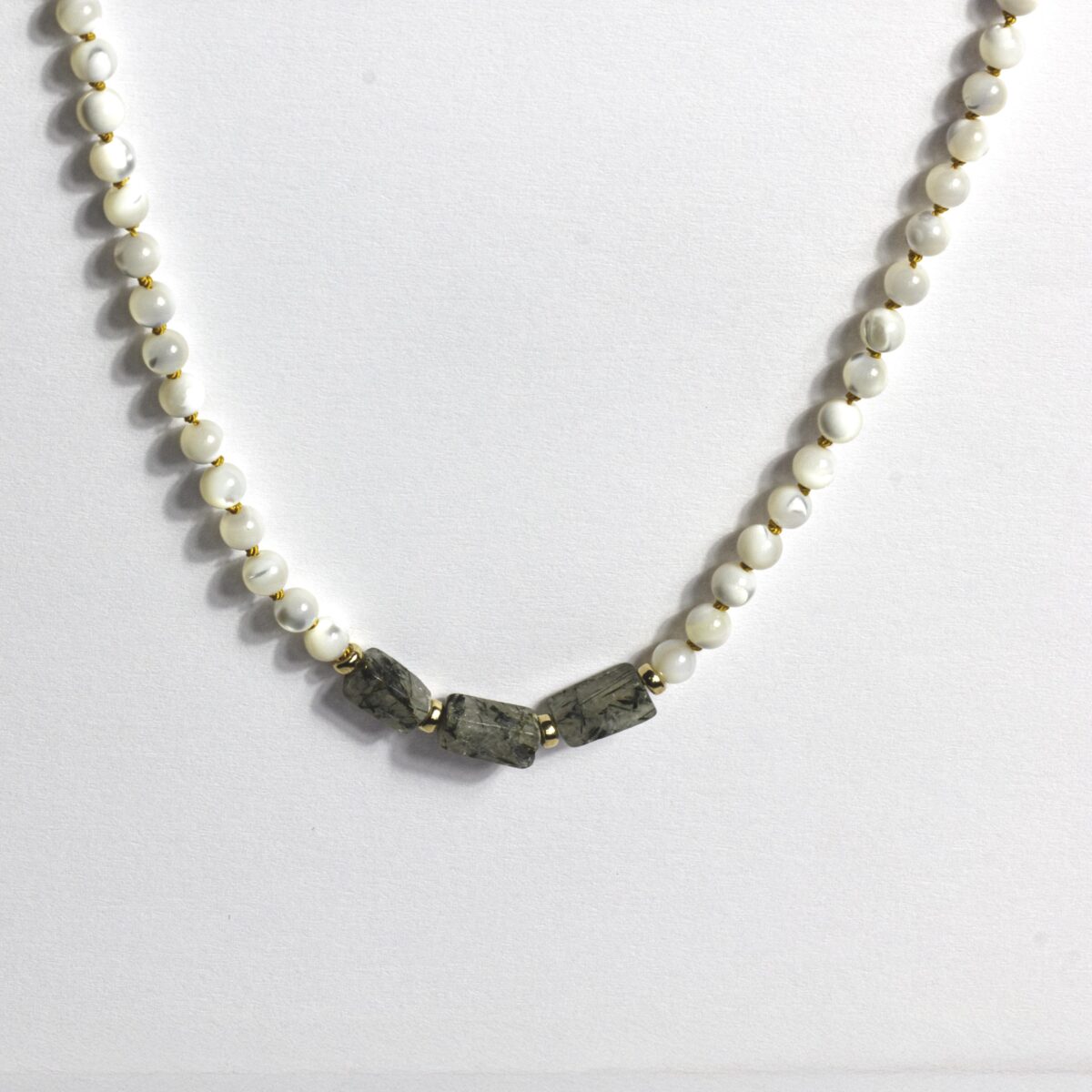 Close-up of a handcrafted necklace featuring round Mother of Pearl beads, three rectangular Tourmaline Quartz stones at the center, and gold-filled spacers, laid on a white background