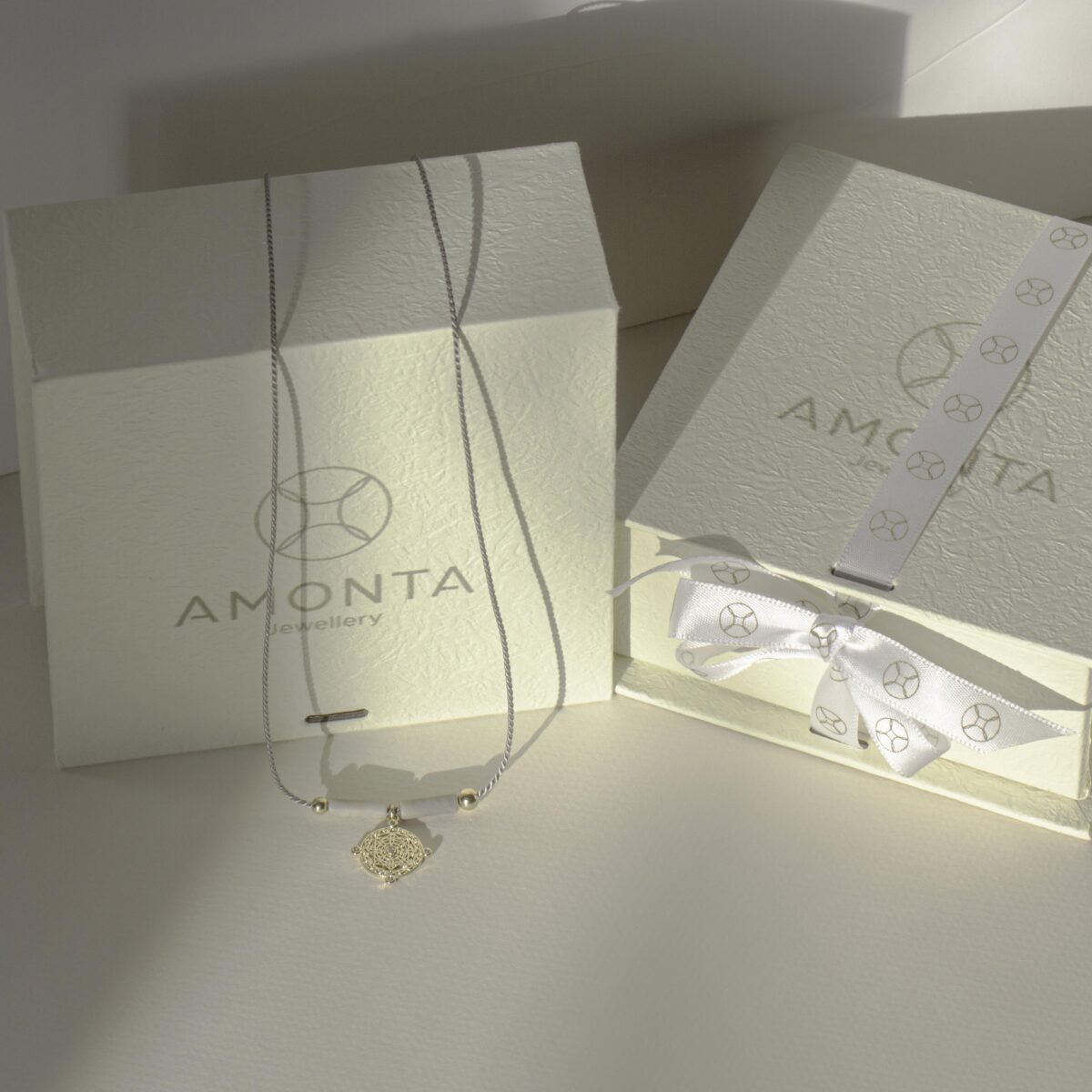 Picasso Jasper necklace with gold-filled pendant displayed in front of AMONTA jewellery gift boxes, styled in soft natural light with elegant packaging