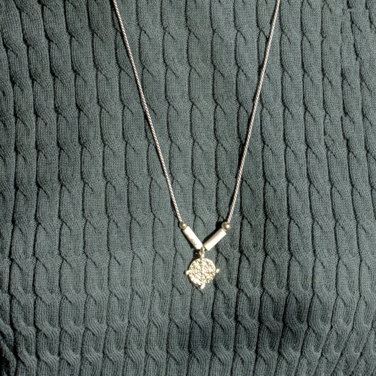 Picasso Jasper necklace with gold-filled pendant and silk thread, worn over a textured green knit sweater in natural light