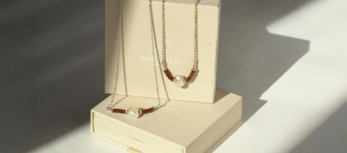 Heart-shaped pearl and ruby necklace on sterling silver chain, displayed in warm sunlight — a symbolic jewellery piece representing eternal love and emotional depth.