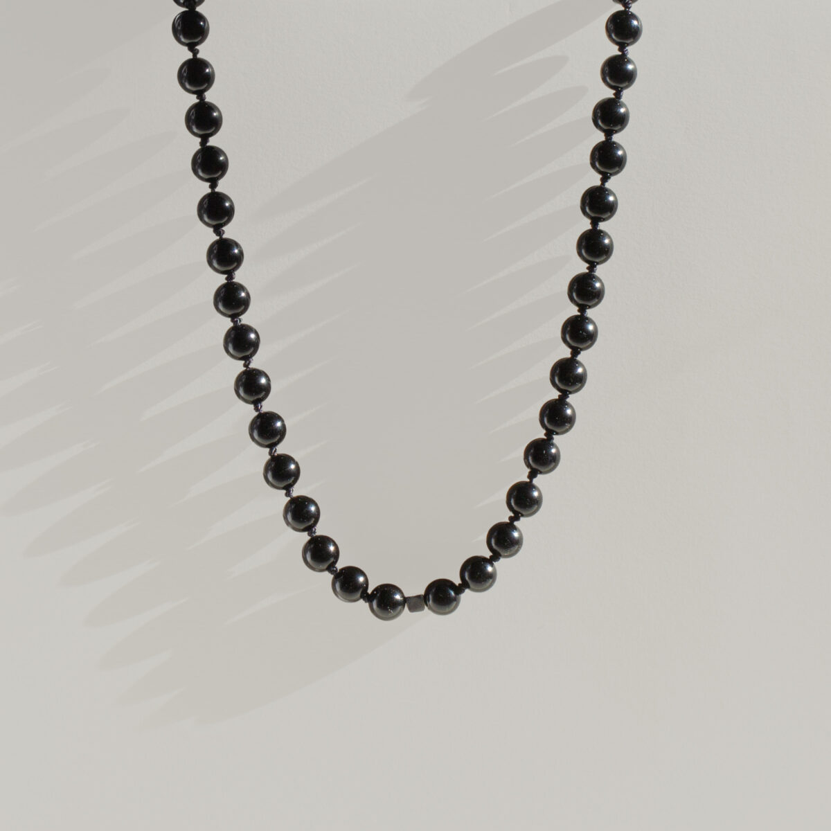 Midnight Edge Men’s Necklace featuring smooth black agate beads and sterling silver spacers on black silk thread.