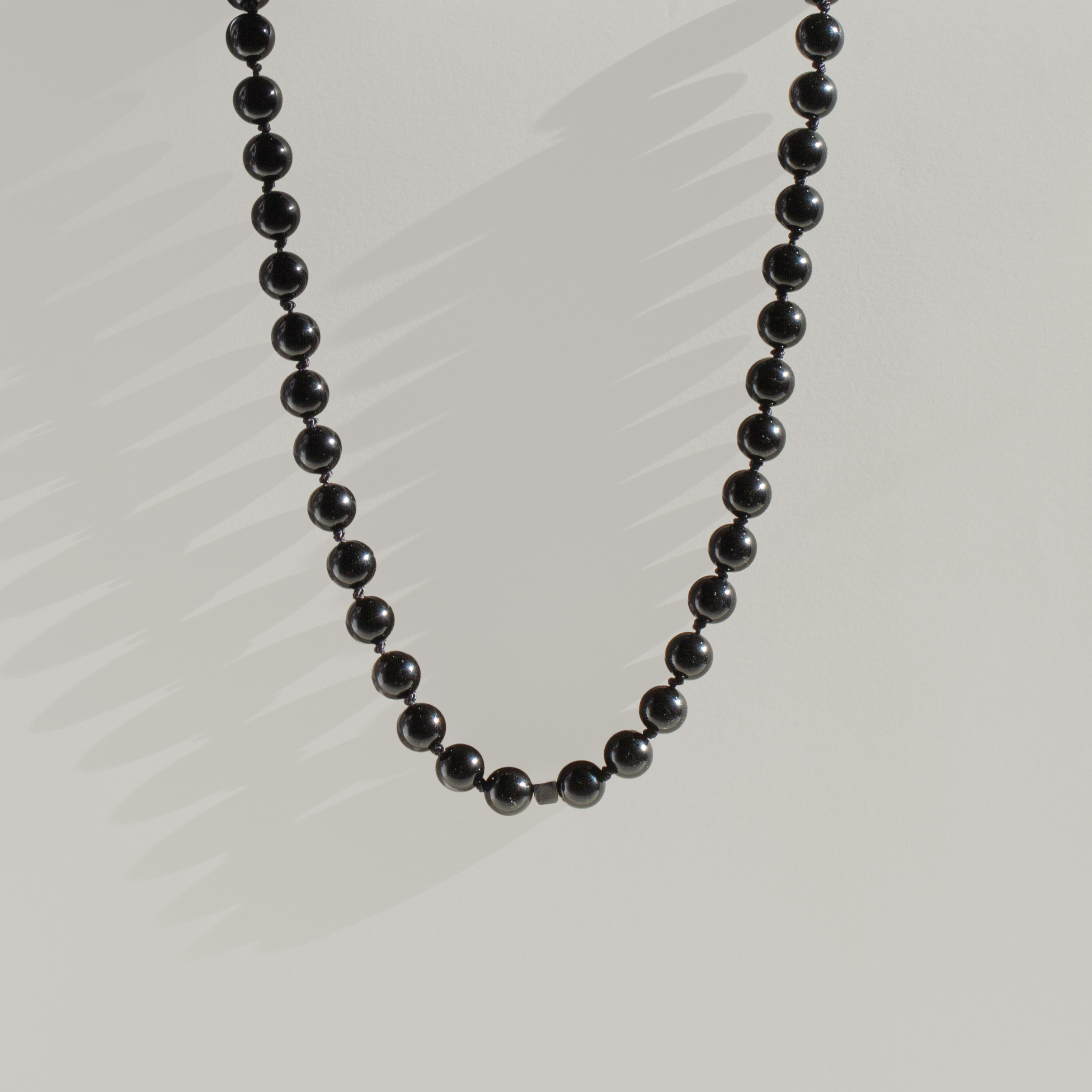 Midnight Edge Men’s Necklace featuring smooth black agate beads and sterling silver spacers on black silk thread.
