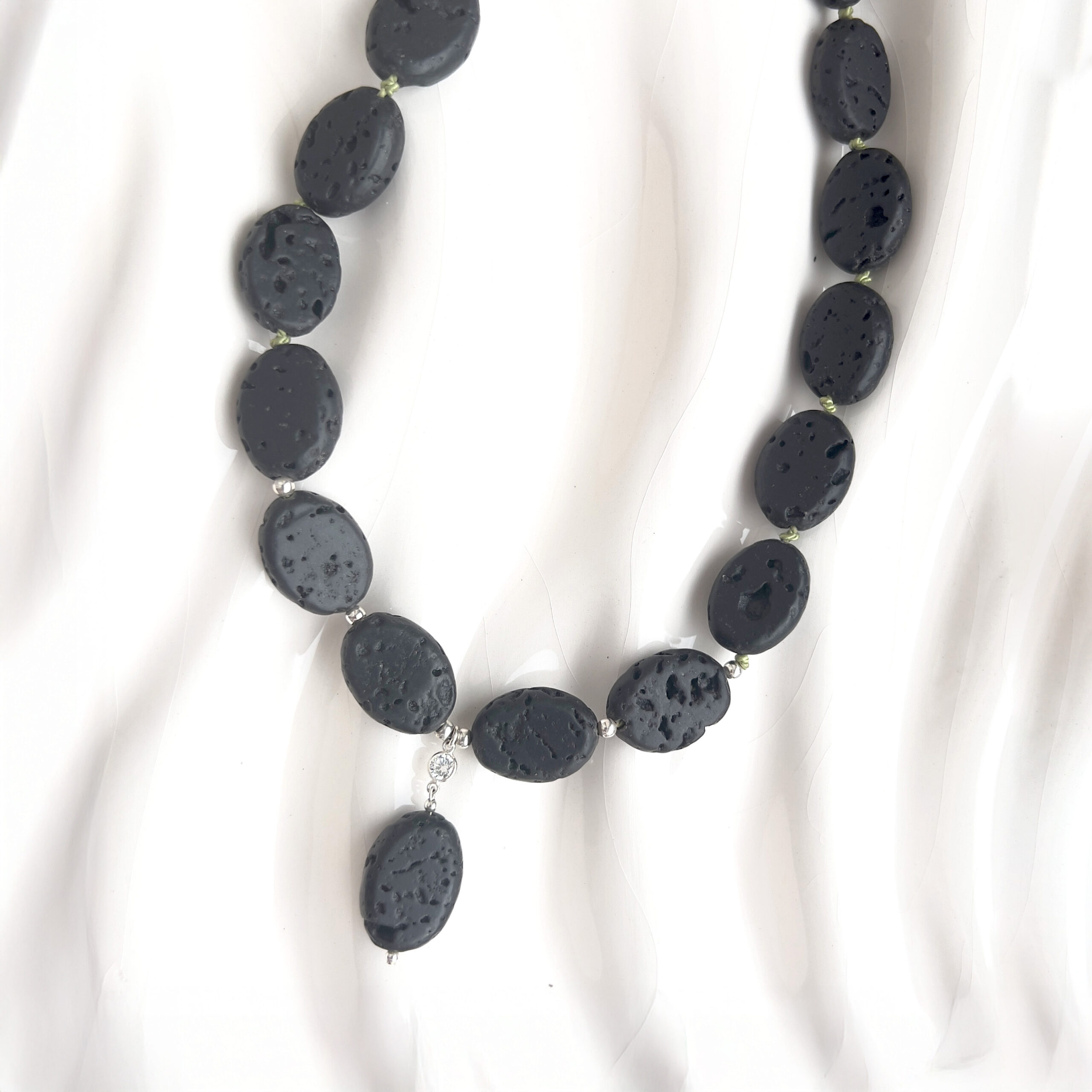 Close-up of the Midnight Lava Necklace featuring natural black lava stones, green silk thread, cubic zirconia, and sterling silver clasp. A bold handcrafted design by AMONTA Jewellery