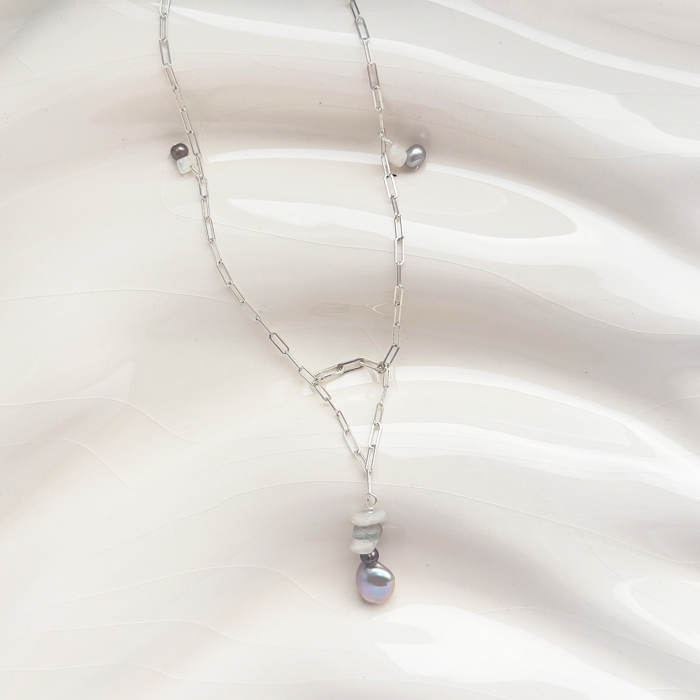 Delicate silver chain necklace with moonstone and grey pearl pendant arranged in a soft triangular form
