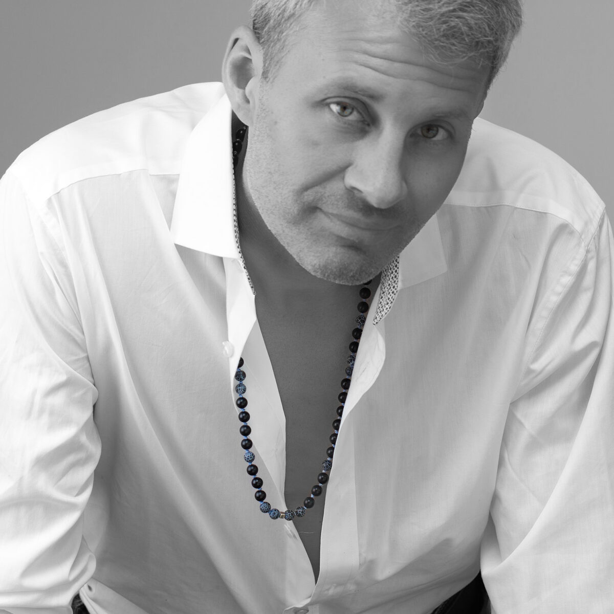 Man wearing Resolve lapis, lava and sterling silver cube necklace by AMONTA Jewellery, hand knotted with natural gemstones.