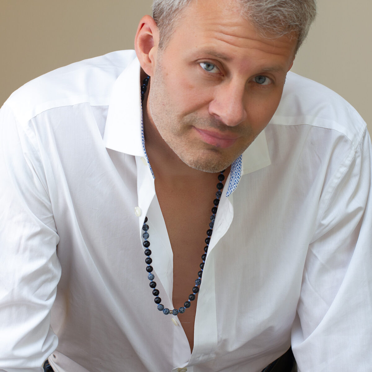 Man wearing Resolve lapis, lava and sterling silver cube necklace by AMONTA Jewellery, hand knotted with natural gemstones.